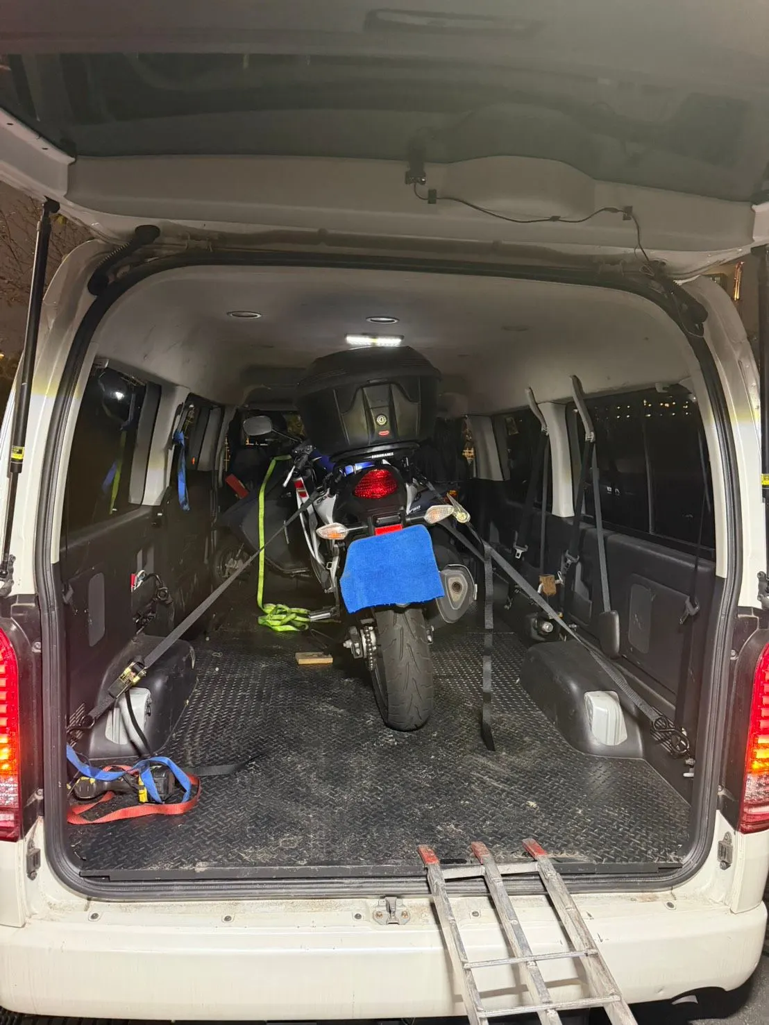 バンの荷室で、バイクをラチェットベルトで固定している